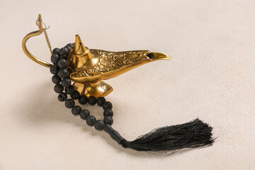 Aladdin lamp with prayer beads for Ramadan on white grunge background
