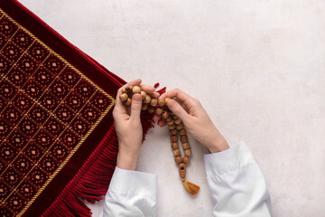 Female hands with Koran and prayer beads for Ramadan on white grunge background