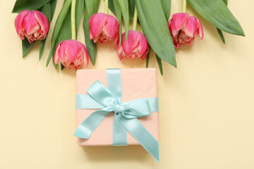 Gift box and bouquet of beautiful tulips on yellow background. International Women's Day