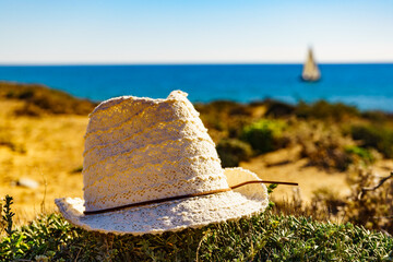 Coast view with summer hat and yacht sailing on sea
