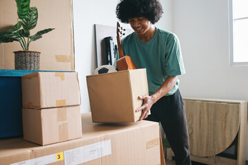 Happy smiling Asian man holding boxes with stuff at new home. Moving, people and real estate concept
