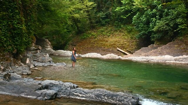 Man walking on the rocky river in paradise place. Creative. Woman cooling her feet in cld mountain stream.