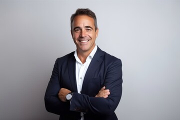 Portrait of a happy mature businessman standing with arms crossed against grey background