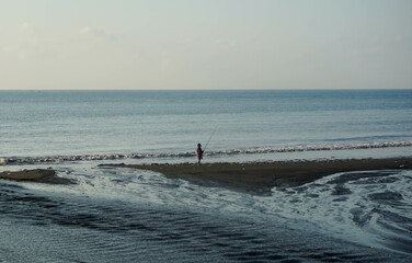 A man fishing at the beach.