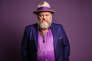 Handsome senior man with long beard and mustache wearing a purple top hat and purple shirt.