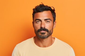 Portrait of handsome man with beard and mustache looking at camera over orange background