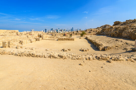 View of the ruins and excavations of the ancient Tylos Fort, a coastal fortress adjacent to Qal'at al-Bahrain fort, with the modern skyline of Manama, Bahrain in the distance.