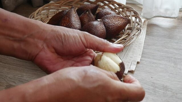 a man peels salak fruit or snake fruit (salacca zalacca), indonesian native fruit.