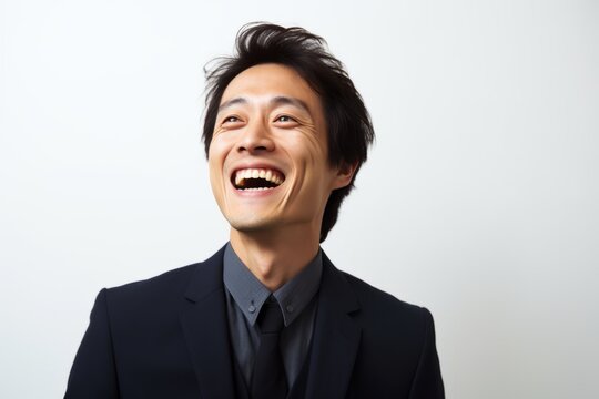 Portrait of happy young asian business man laughing over white background