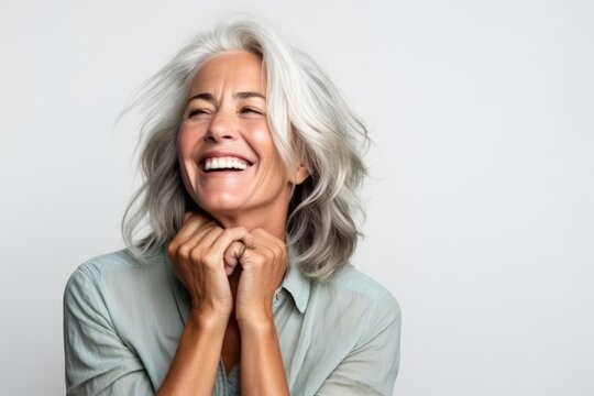 Portrait of a happy senior woman laughing with hands clasped together