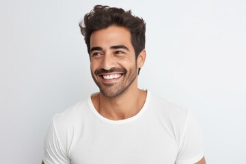 Handsome young man in white t-shirt looking at camera and smiling while standing against grey background
