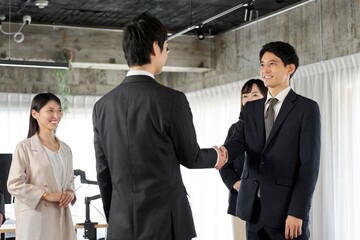 オフィスで握手をするアジア人ビジネスパーソン