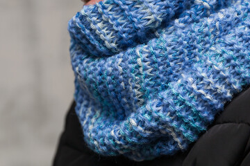 Blue handmade knitted textured snood scarf on a girl's neck close up