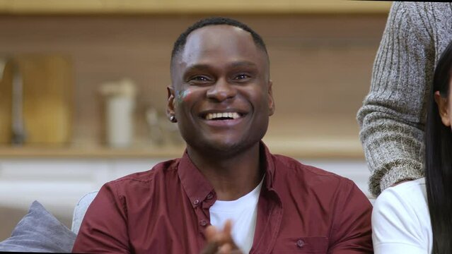 A handsome dark-skinned young male fan in close-up watches the game of his favorite team and suddenly they win. The favorite team of fan wins, the fan is happy about the goal scored and the victory.
