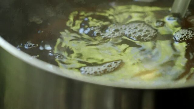 魚・魚介類でスープの出汁をとる調理　湯気を出し煮立つ水面に反射する光と沸騰して泡立つスープ　レストラン・シェフ・料理