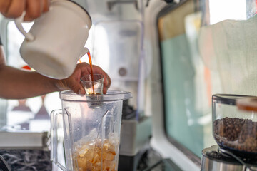 Barista pouring coffee to a blender to prepare iced coffee