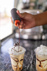 Worker garnishing a frappe with caramel on top