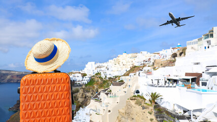 Summer concept with orange luggage with hat and landscape view of Oia town in Santorini island in...