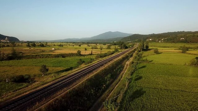 Train move on railway wonderful moment cinematic perspective scenic landscape of Hyrcanian forest mountain view panoramic green meadow rice paddy farm land field summer agriculture iran gilan travel