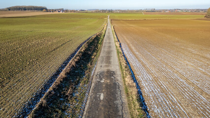 This image taken from above showcases a rural country road stretching into the distance, a straight...