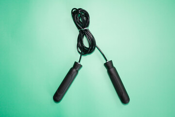 Skipping rope with black handles on the green background. 