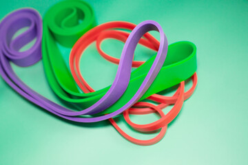 The concept of sports, fitness and a healthy lifestyle. Multicolored fitness rubber bands on a green background. Copy space .