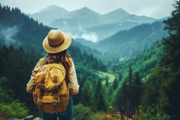 Fototapeta na wymiar Woman traveler with backpack and hat, looking at amazing mountains and forest.