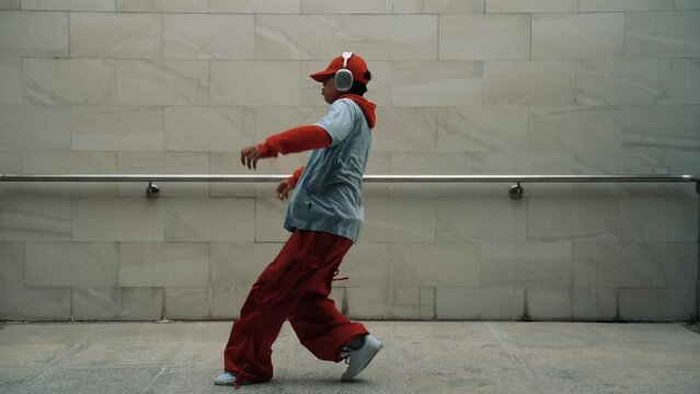 Handsome choreographer practice street dance in gray background. Young attractive b boy dancer perform while wearing stylish cloth. Feeling of lively step. Copy space. Outdoor sport 2024. Sprightly.