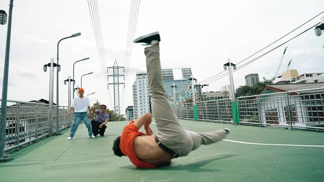Professional hipster doing head spin while friend dancing break dance together. Group of street dancer perform moving to music while standing and looking at camera. Outdoor sport 2024. Sprightly.