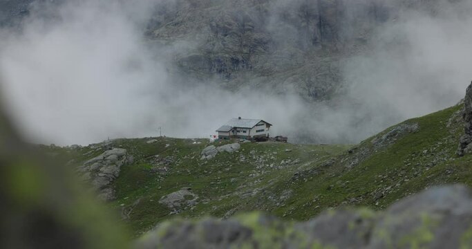Incredible scene of chalet house on top of mountain hill, seen through rocks