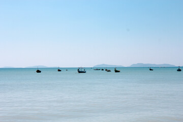 Smooth sea view with no waves and many fishing boats in the distance with sky and blue sea.