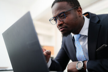 Young it-engineer Senior Programmer of African ethnicity working with coded data while sitting in an armchair in front of a computer in the office