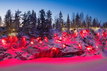 Red night lighting of the wall of Ruskeala Marble Canyon on a January evening. Mountain park of...