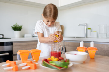 Portrait of cute child girl making ice cream. Kid have fun making with homemade fruit puree ice...