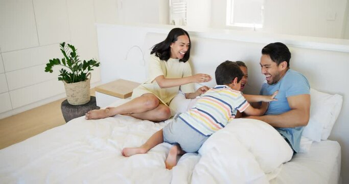 Family, laughing for tickle and parents with kids on bed in home together for weekend bonding. Love, smile or happy with funny mother, father and sibling kids having fun in bedroom of apartment