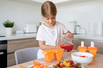 Portrait of cute child girl making ice cream. Kid have fun making with homemade fruit puree ice...