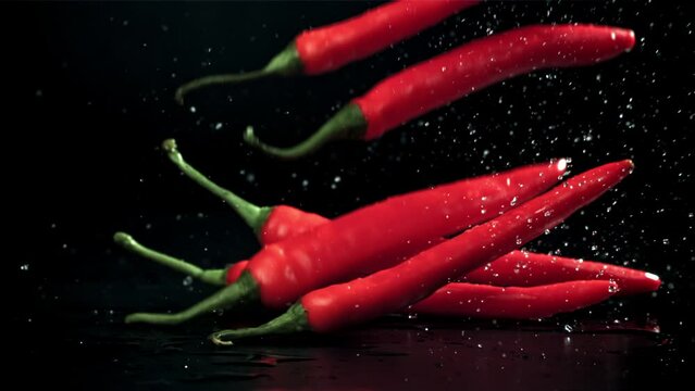 Chili peppers fall on a wet black table. Filmed on a high-speed camera at 1000 fps. High quality FullHD footage