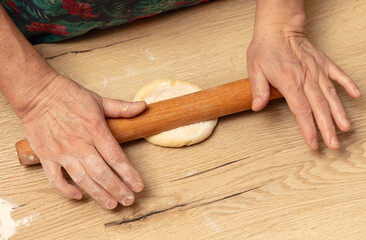 A woman rolls out dough with a rolling pin