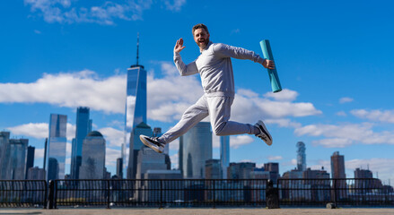 Sport lifestyle. Sportsman running with fitness mat. Sport man training outdoor in New York....