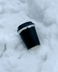 Black paper cup on the snow