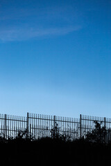 Silhouette of metal fence and empty blue sky on sunse