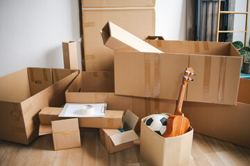 Open cardboard logistic boxes with housing stuff. Messy containers placed on floor of new home,...
