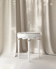White vintage victorian style table podium in sunlight with beige brown curtain in background for...