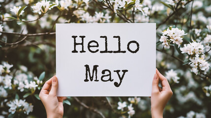 cropped view of woman holding card with hello may lettering near blooming tree