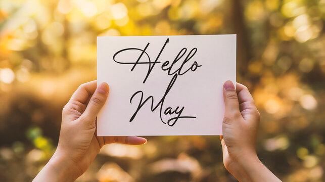 cropped view of woman holding card with hello may lettering near blooming tree