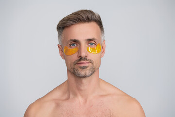 Spa care. Eye patch. Beauty man face with under eye collagen pads. Mature man has fresh healthy skin with collagen patches under eyes. Facial treatment. Man applying eye patches. Use a cold compress