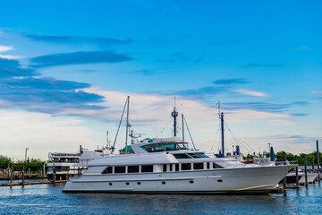 Naklejka premium Yacht vacation in summer. A luxury private motor yacht in sea harbor. Yacht in navigation. Private white luxury anchored off the beach. Summer vacation. Summertime yachting. Coastline