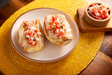 Molletes. Mexican recipe based on bolillo bread split lengthwise, spread with refried beans and gratin cheese, adding pico de gallo sauce and some protein such as ham, bacon or chorizo.
