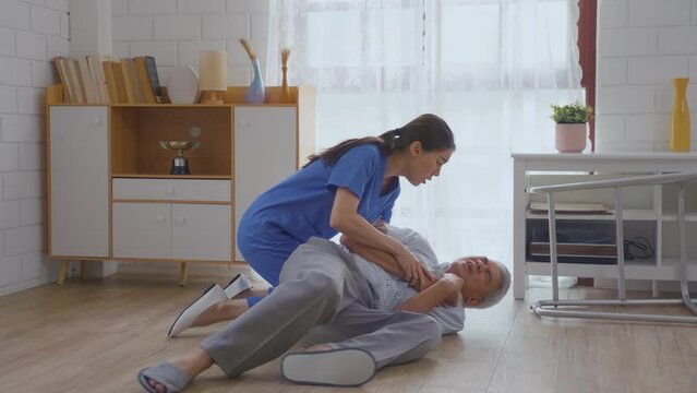 Asian caregiver helping senior male from falling on the ground at home. 