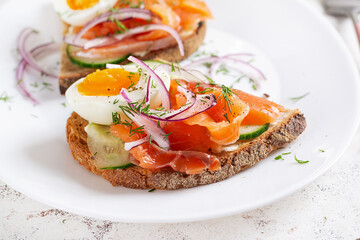 Delicious toast with salmon, boiled egg, cucumber and cream cheese on a white plate. Healthy eating, breakfast. Keto diet food. Tasty food.